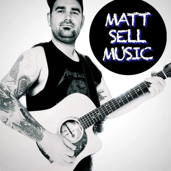 A man with dark hair and tattoos holding a guitar