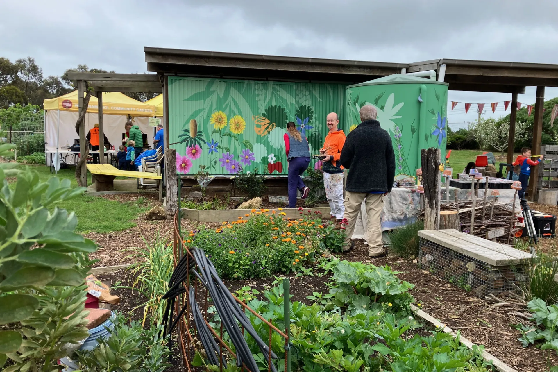 A community garden full of lush garden beds, people and art